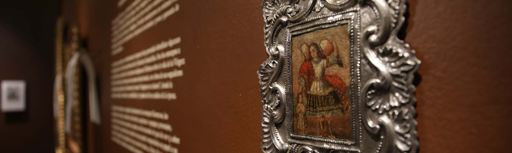 Pintura colonial de un arcángel enmarcada sobre muro café y texto blanco